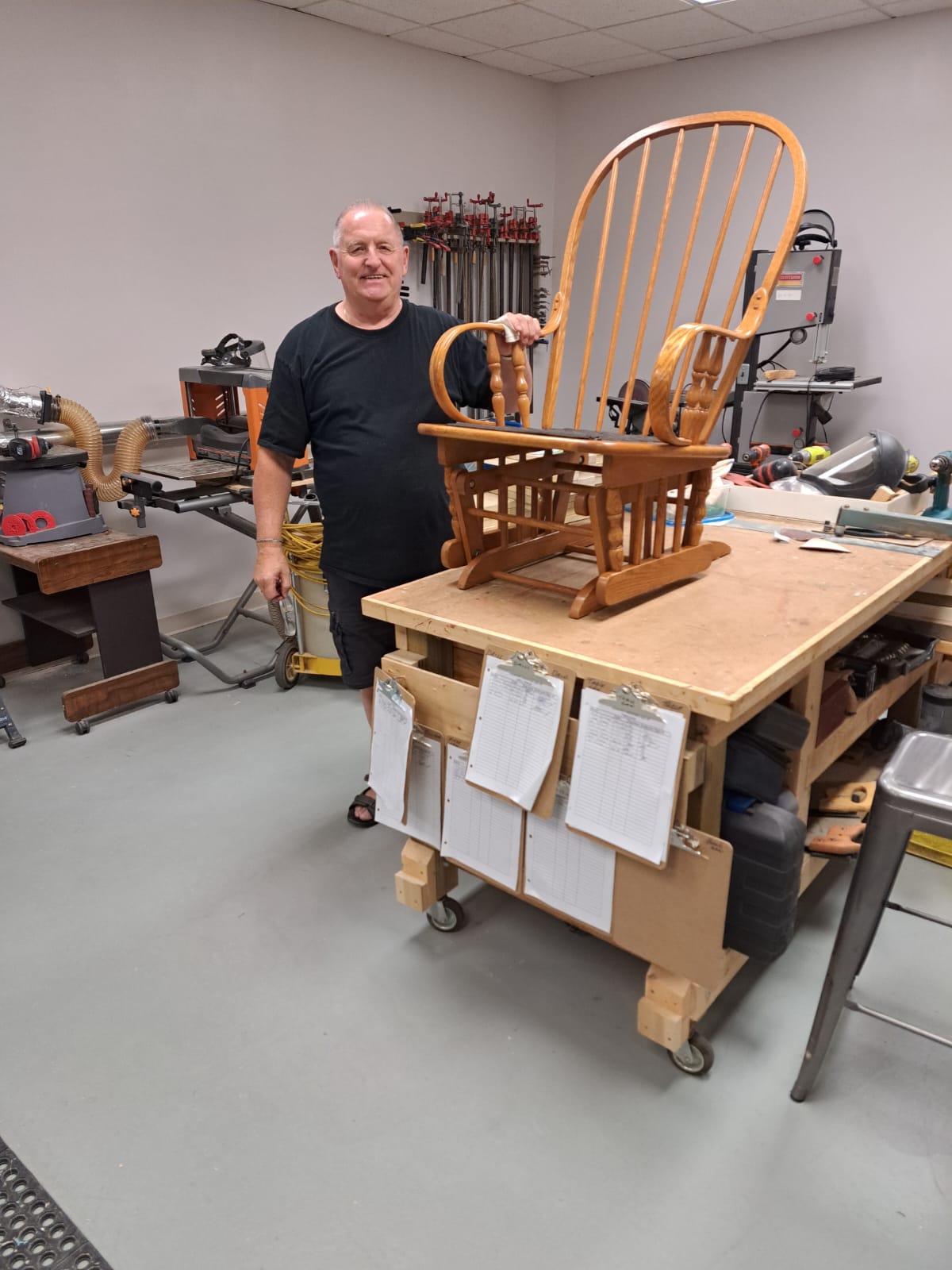 A member stands next to a repaired chair.