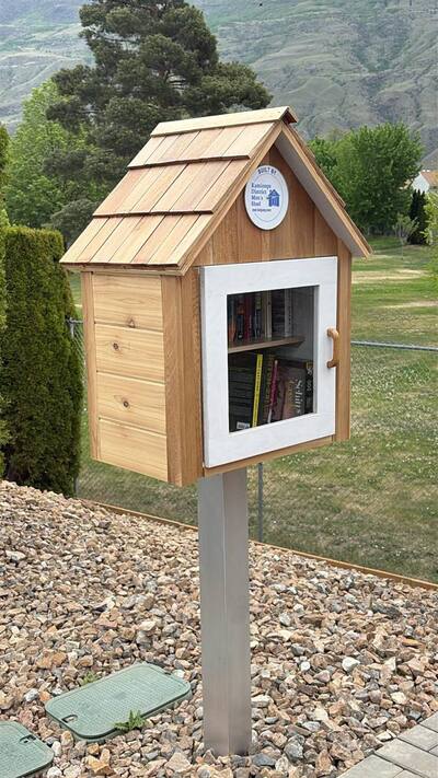 Front view of a TNRL lending library, showing the glass door and KDMS plaque.